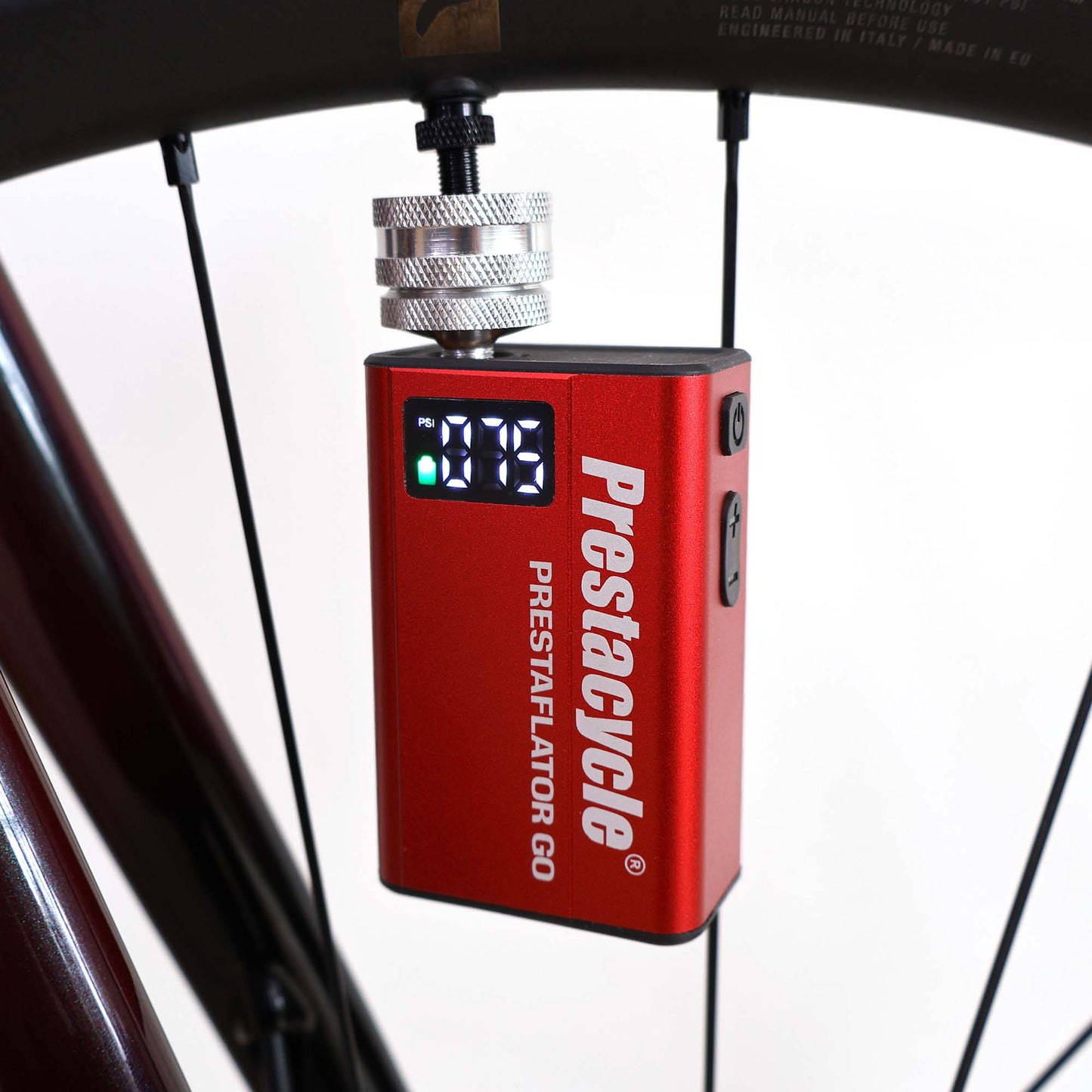A red Prestacycle Prestaflator GO Portable Digital Rechargeable Preset Bicycle Tire Inflator, perfect for electric bikes, is connected to a bicycle wheel and shows the pressure reading on its display.