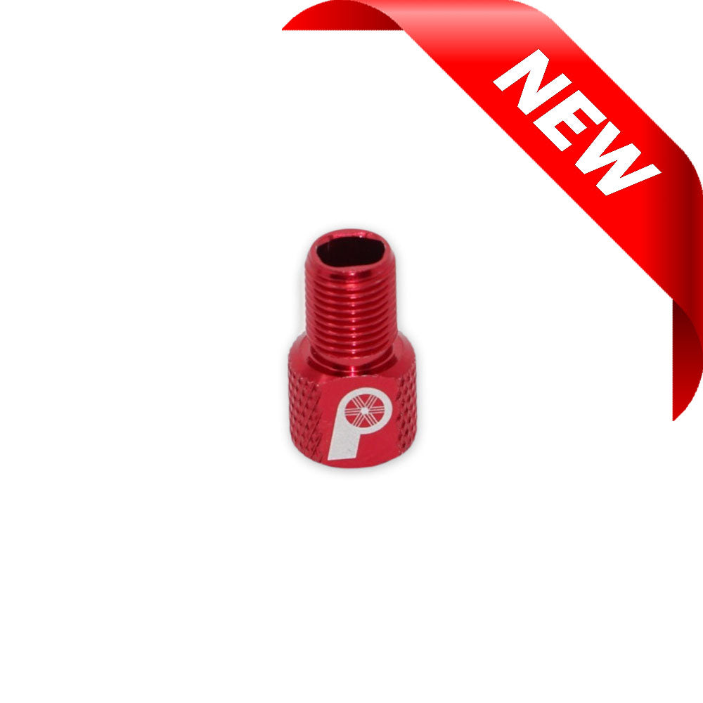 Red Prestadapter TUBELESS – Presta adapter and valve core remover, made from lightweight alloy with a knurled grip and white logo, centered on a white background. A red ribbon labeled NEW is shown in the top right corner.