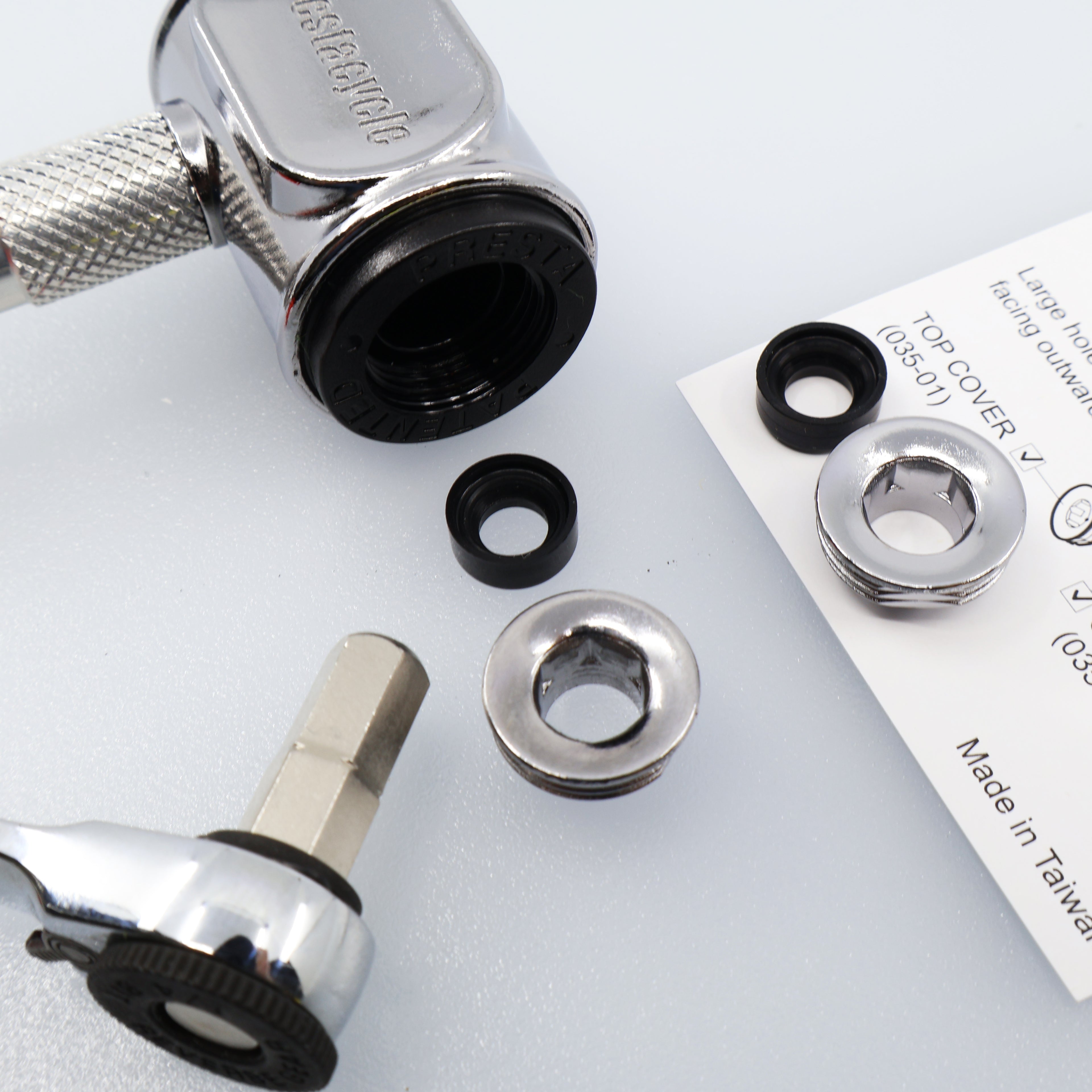 A close-up of a Prestaflator Pro Presta Head Rebuild Kit shows a ratchet tool, chrome washers, black rubber gaskets, and an instruction sheet neatly arranged for replacing pump head seals on a light surface.