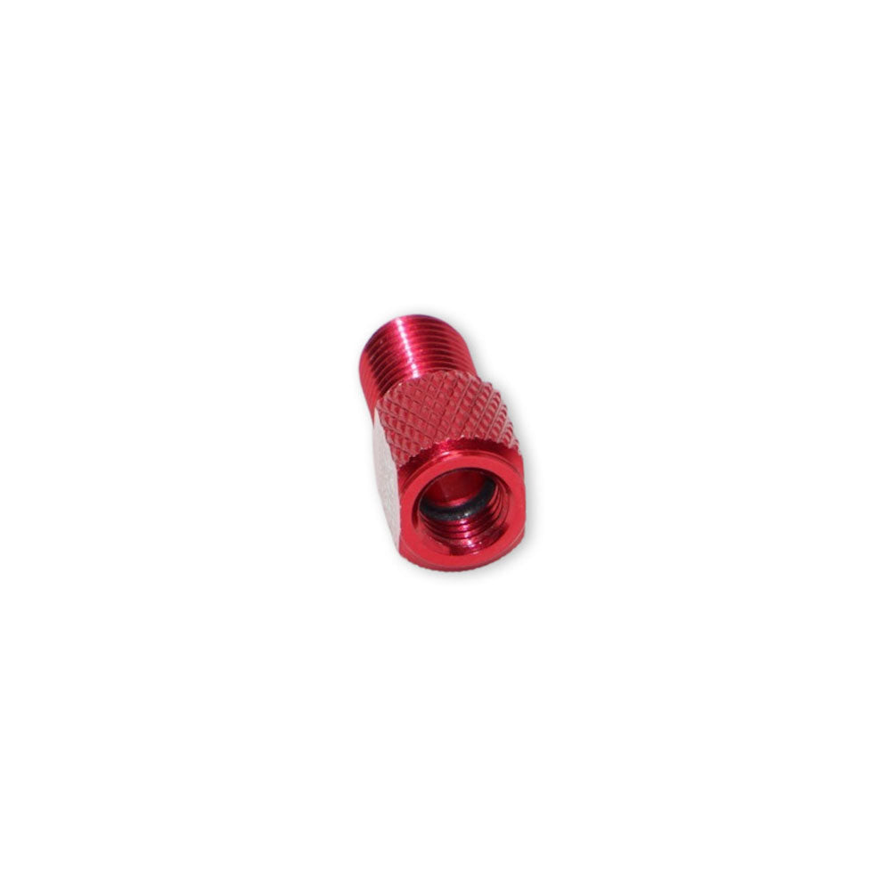 The Prestadapter TUBELESS is a small, red, lightweight alloy Presta adapter and valve core remover with a knurled grip, compatible as a Schrader to Presta valve adapter, shown against a plain white background.