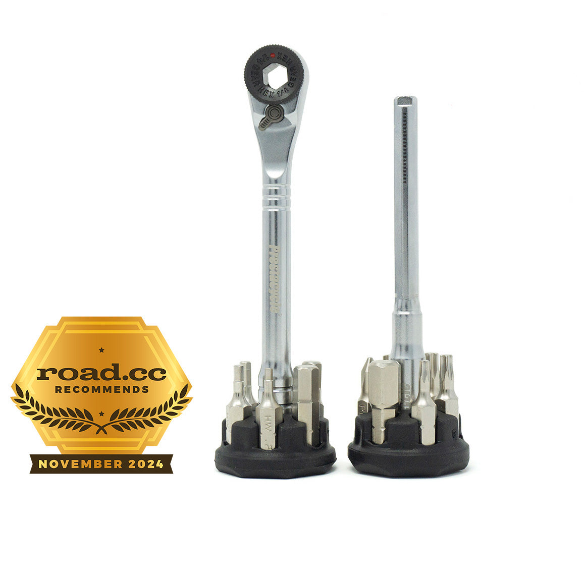 Two Prestacycle Pro T-Handle Kits with 12 S2 bits and 2 round holders stand upright on black bases. A gold “road.cc recommends November 2024” badge is displayed to the left of the tools.