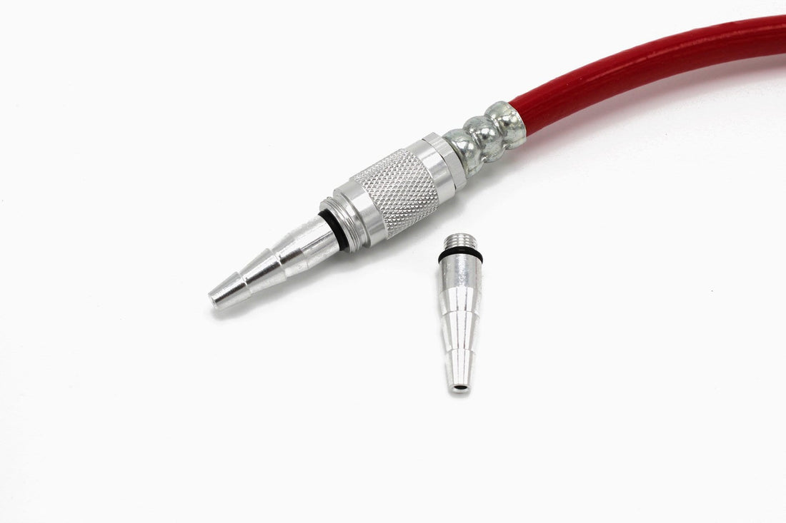 A close-up of a red hose with a metal quick-connect fitting attached, shown next to the Prestacycle Safety Blower / Low Pressure Inflator Tip nozzle on a white background.